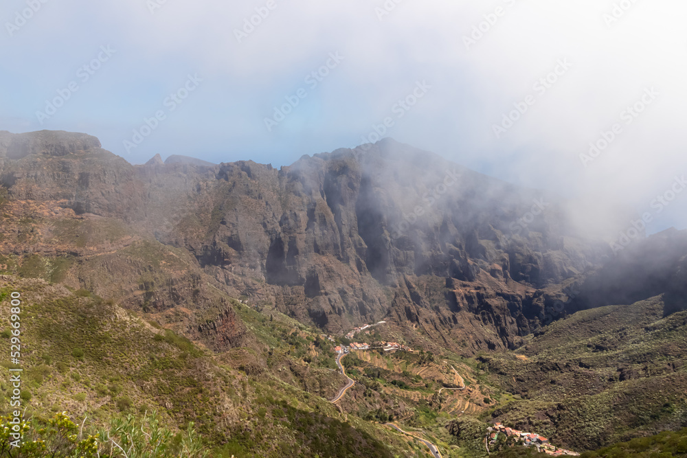 Scenic view on the steep canyon of the Teno mountain massif, Tenerife, Canary Islands, Spain, Europe. Hiking trail between village Masca and Santiago del Teide. View from Cruz de Gala. Clouds coming Scenic view on the steep canyon of the Teno mountain massif, Tenerife, Canary Islands, Spain, Europe. Hiking trail between village Masca and Santiago del Teide. View from Cruz de Gala. Clouds coming