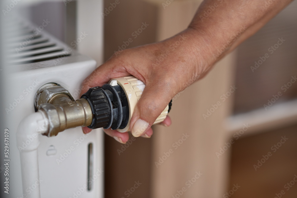 A woman's hand turns the radiator A woman's hand turns the radiator