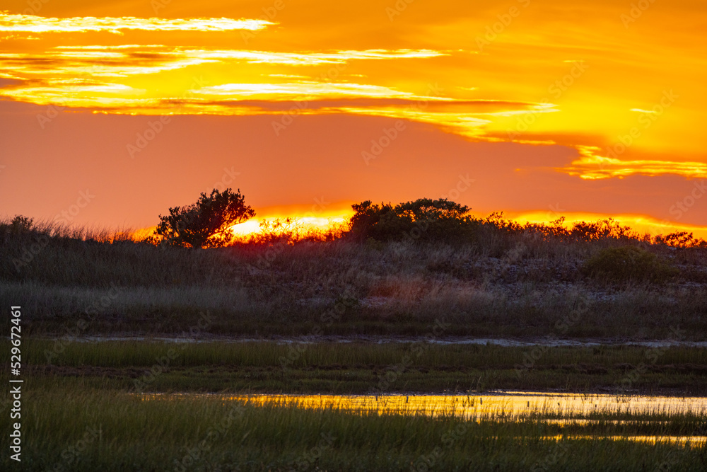 Sunset Over Wetland Landscape With Shades Of Orange Created A Scenic Breathtaking View By Dramatic Clouds In The Sky