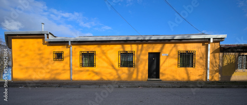 Fototapeta Naklejka Na Ścianę i Meble -  One floor traditional yellow adobe house in a small south ameruican town during sunny day, Talca, Chile, view from the street