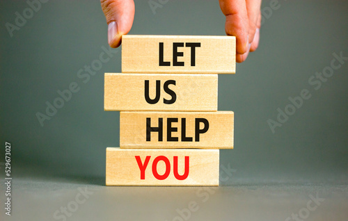 Support and let us help you symbol. Concept words Let us help you on wooden blocks on a beautiful grey table grey background. Businessman hand. Business, support and let us help you concept.