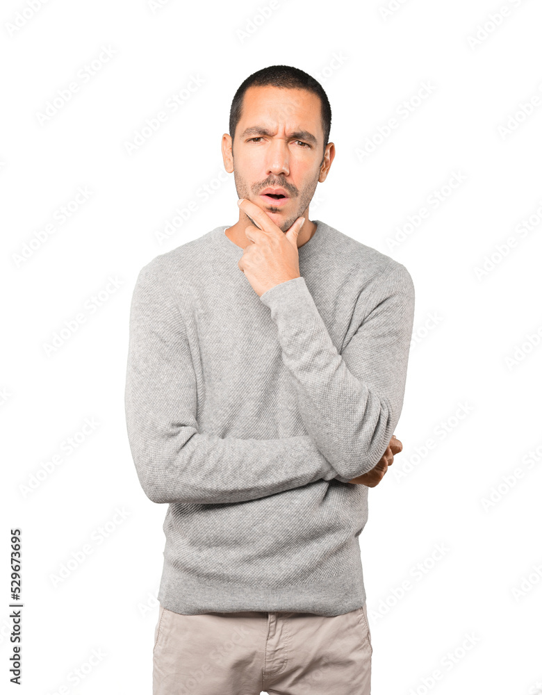 Concentrated young man making a gesture of distrust Concentrated young man making a gesture of distrust