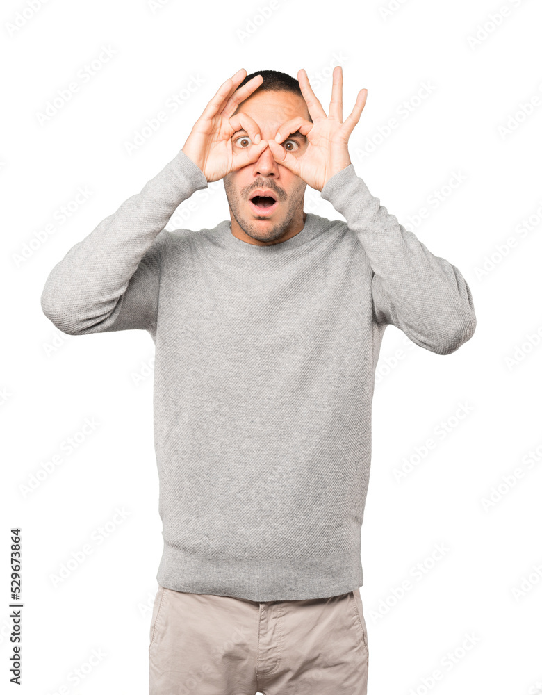 Amazed young man using his hands like a binoculars Amazed young man using his hands like a binoculars
