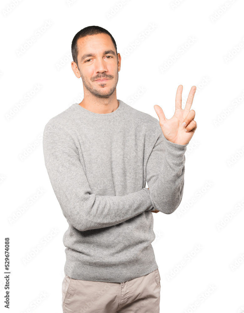 Fototapeta premium Young man making a number three gesture