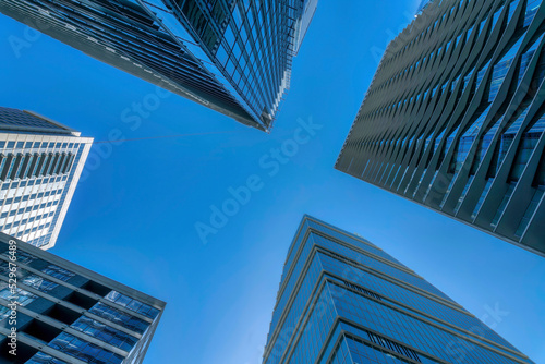 Looking up at the cloudless blue sky with towering skyscrapers apartments