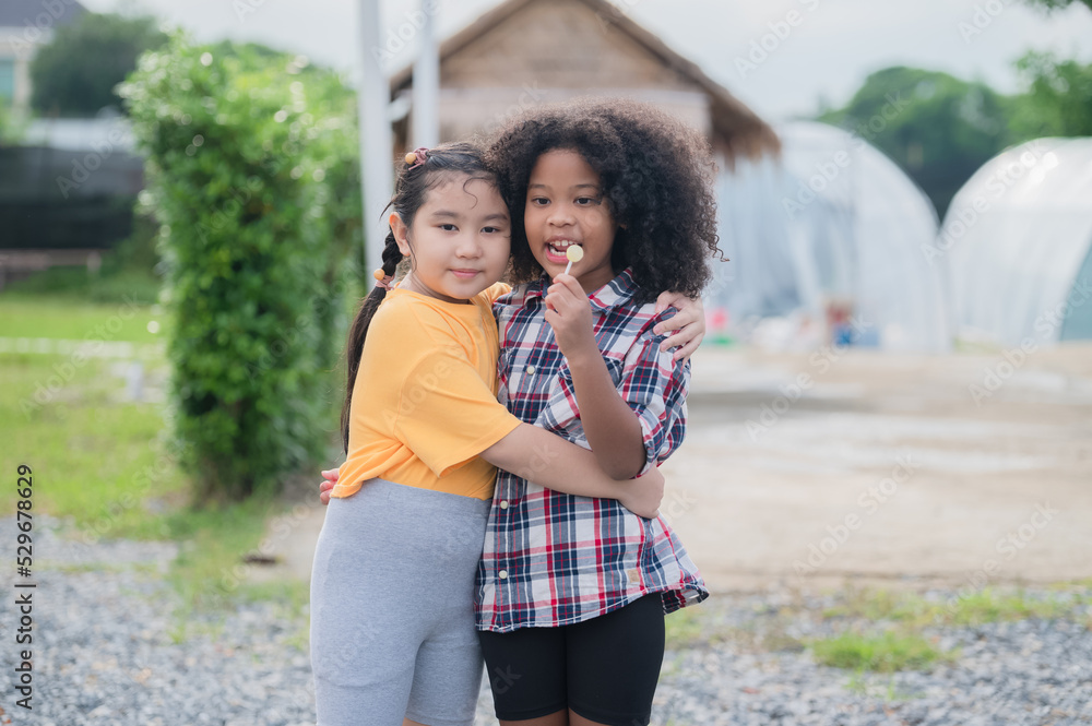 Two kids friends hugging outdoor having fun in summer.