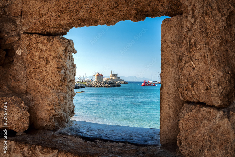 Windmills and saint Nicholas fortess in town Rhodes. View from window in the walls. Rhodes island in Greece