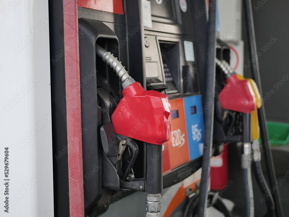 man hand holding a green gas nozzle. A man's hand is pulling the fuel dispenser out of the red meter cabinet. E20 uses a green fuel nozzle. Woman is holding a gasoline fuel pistol at gas station. man hand holding a green gas nozzle. A man's hand is pulling the fuel dispenser out of the red meter cabinet. E20 uses a green fuel nozzle. Woman is holding a gasoline fuel pistol at gas station.