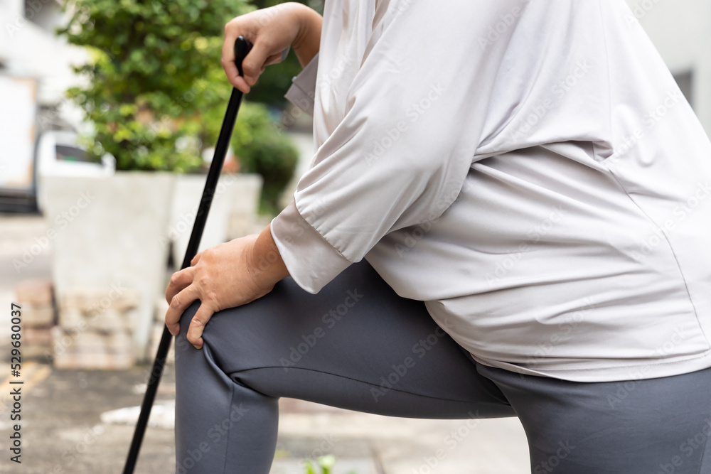 old senior woman with knee pain, osteoarthritis, osteoporosis using walking cane or walk aid in bad accessibility design city old senior woman with knee pain, osteoarthritis, osteoporosis using walking cane or walk aid in bad accessibility design city