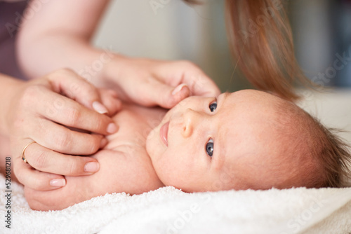Mother Massaging Her newborn baby boy. Realistic home portrait