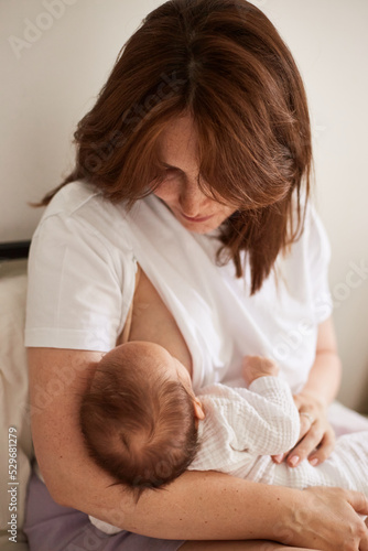 Mother breastfeeding her newborn baby boy. Realistic home portrait