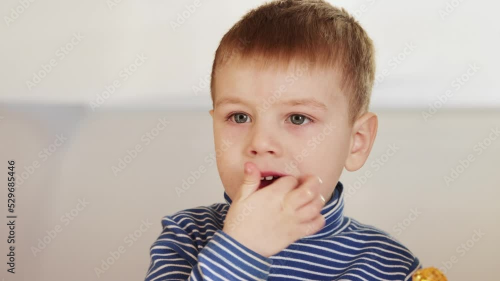 The boy eats candy and tries to get stuck pieces The boy eats candy and tries to get stuck pieces