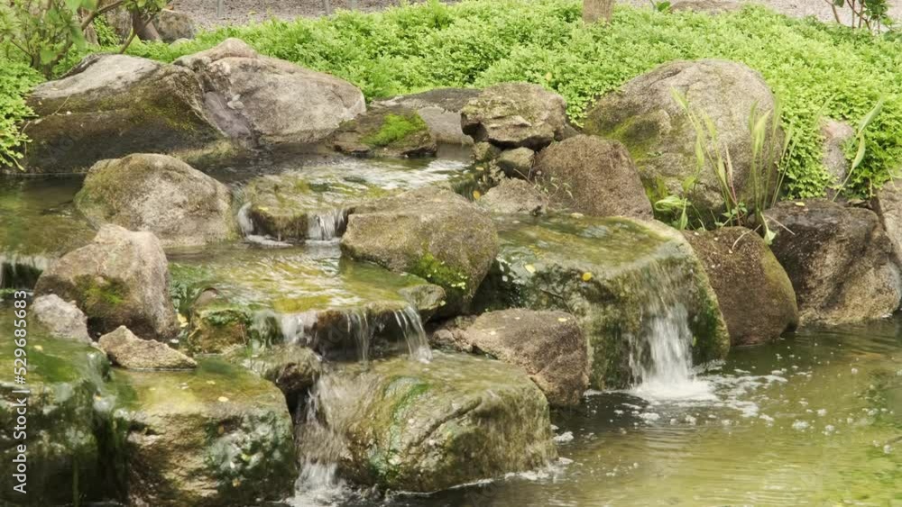 Selective focus. A small decorative waterfall in the Park or in the garden. Landscape design. Waterfall fountain for tropical garden decoration with green plants. Artificial waterfall in the cafe. Selective focus. A small decorative waterfall in the Park or in the garden. Landscape design. Waterfall fountain for tropical garden decoration with green plants. Artificial waterfall in the cafe.