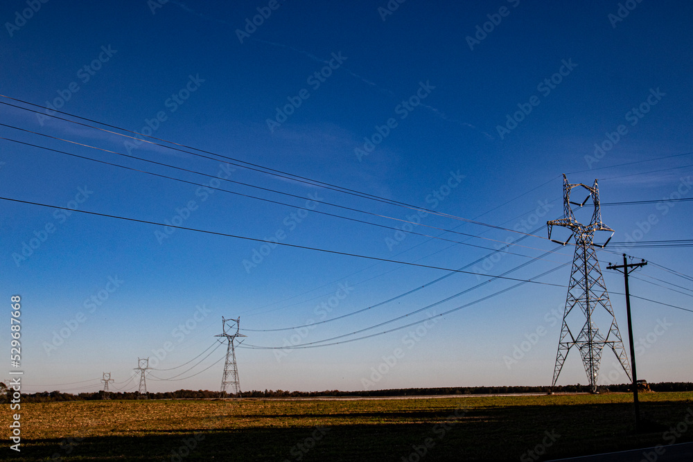 Large power pylon columns and lines running in a line in the country