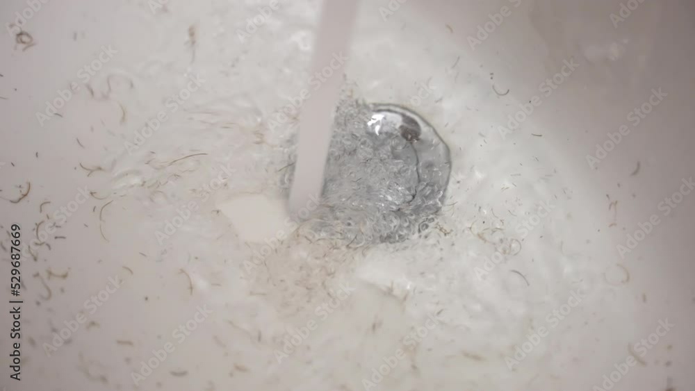Short brown hair inside the white bathroom sink, faucet stream of water
