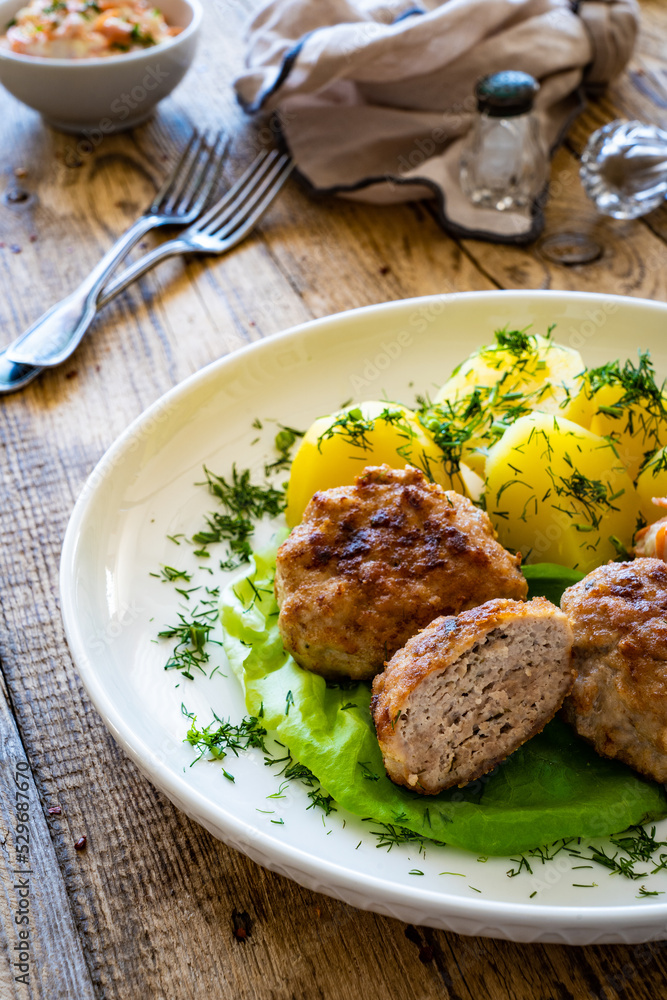 Fried meatballs with boiled potatoes and carrot salad on wooden table
