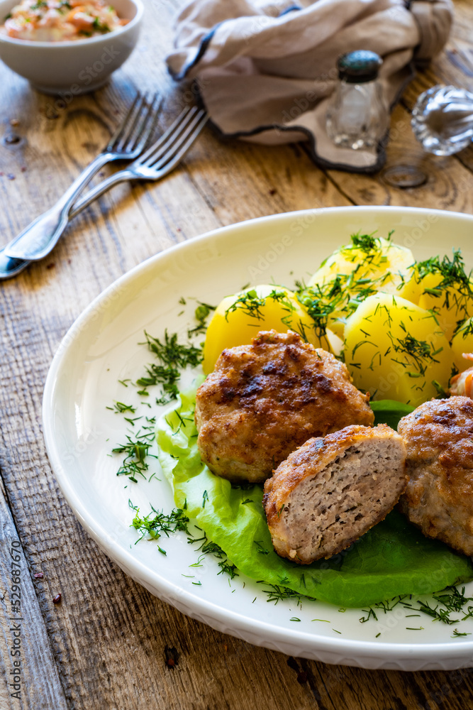 Fried meatballs with boiled potatoes and carrot salad on wooden table
Fried meatballs with boiled potatoes and carrot salad on wooden table