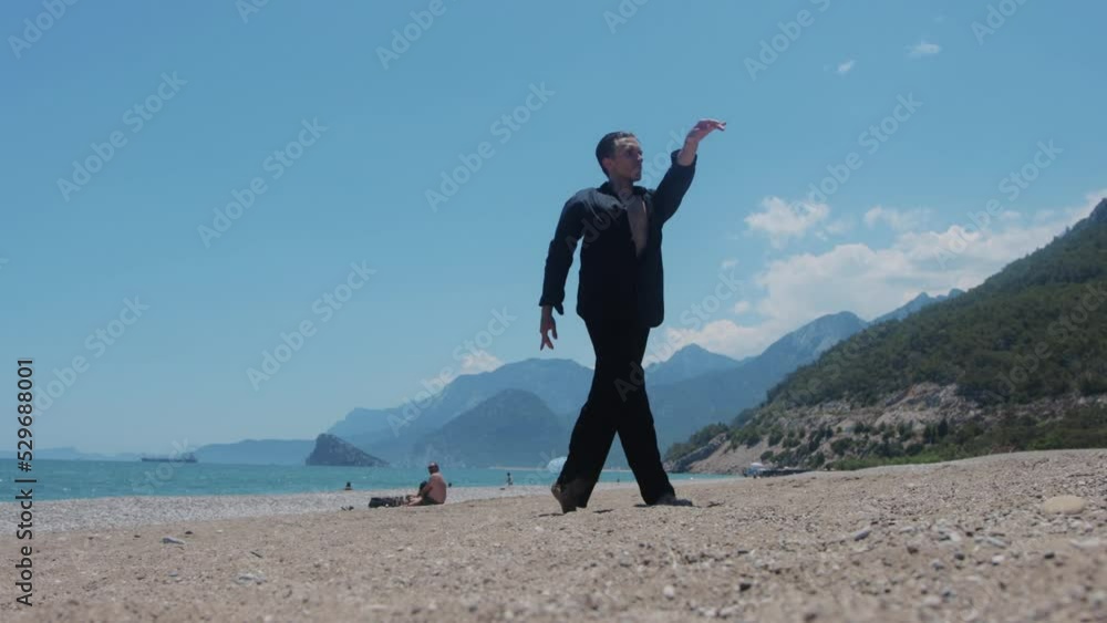 An attractive man in black shirt dancing by the sea An attractive man in black shirt dancing by the sea