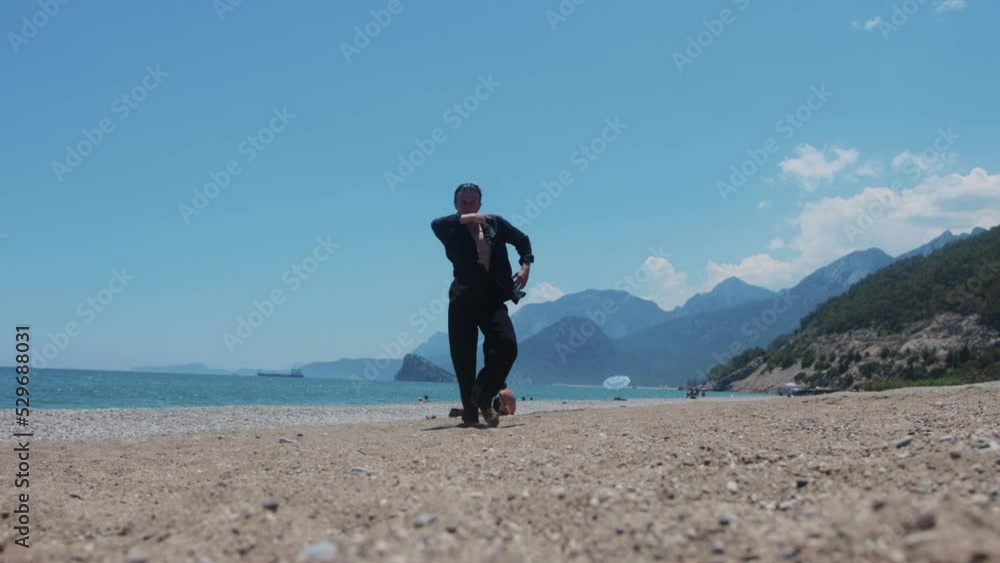 An attractive man in black shirt gracefully dancing on the beach An attractive man in black shirt gracefully dancing on the beach
