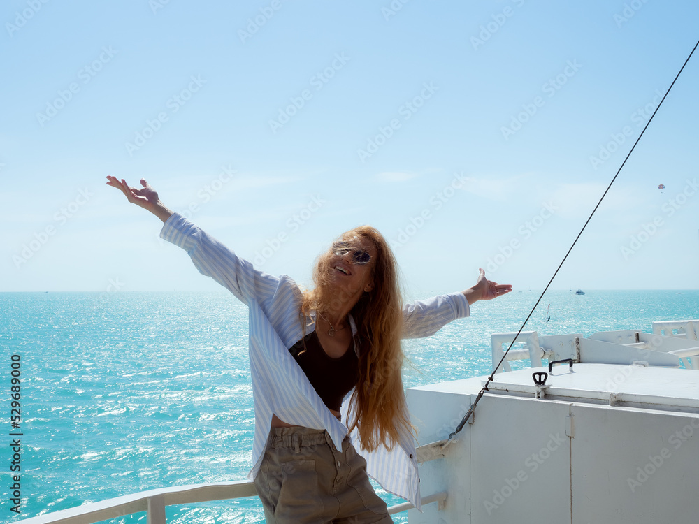 The blonde girl in sunglasses spread her arms to the sides. happy girl sitting on the railing of the ship The blonde girl in sunglasses spread her arms to the sides. happy girl sitting on the railing of the ship