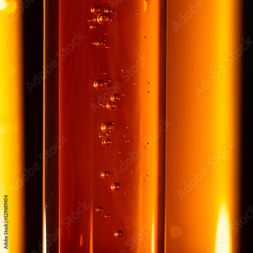 Yellow viscous liquid sunflower lecithin with bubbles in a transparent test tube on a dark background