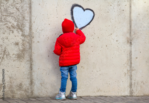 Street artist child painting heart symbol wall world love concept