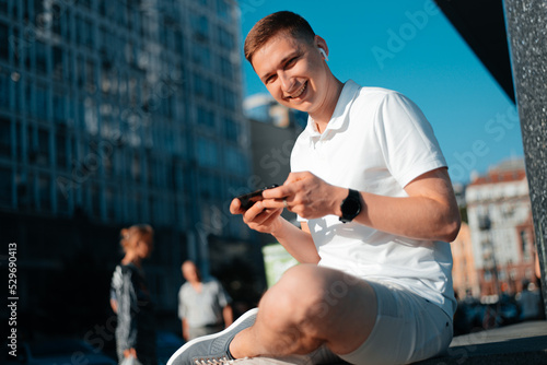 Happy man playing game with smartphone outdoors