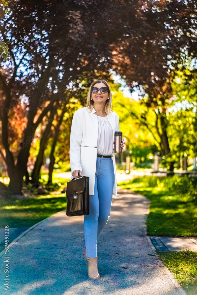 Coffee break - beautiful woman walking in city park Coffee break - beautiful woman walking in city park