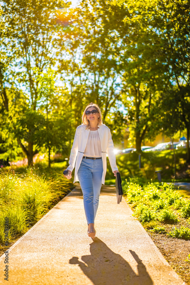 Coffee break - beautiful woman walking in city park Coffee break - beautiful woman walking in city park
