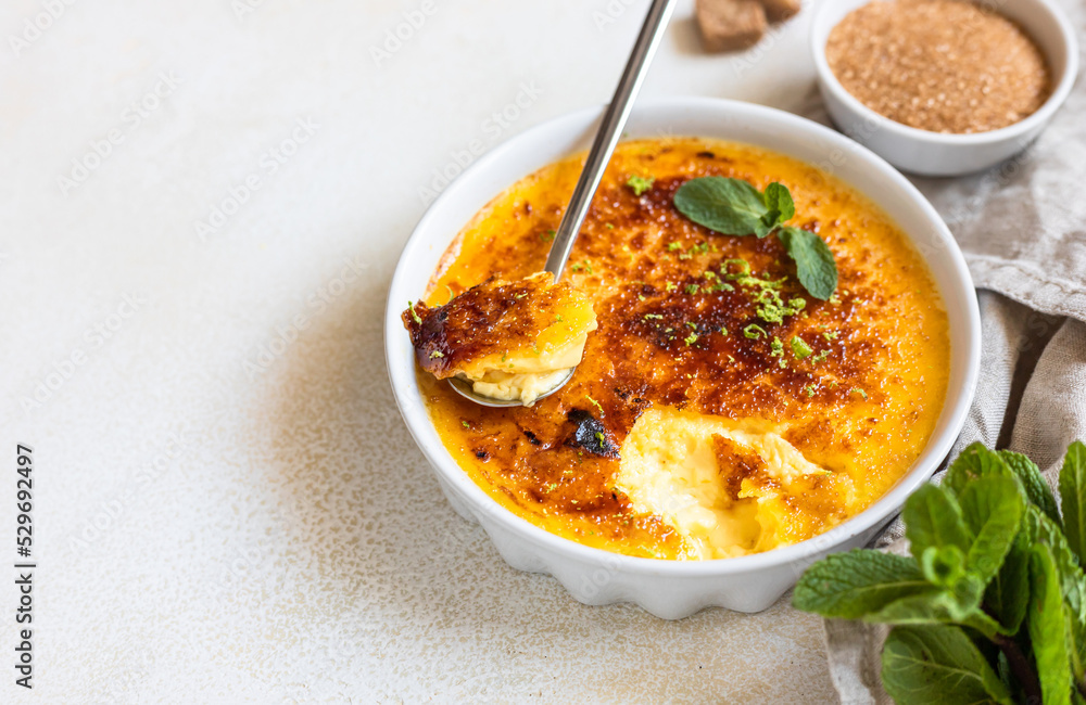 Creme brulee with caramel crust and mint in white ceramic dishes. Famous french dessert. Delicious desserts for cafe or restaurant. Creme brulee with caramel crust and mint in white ceramic dishes. Famous french dessert. Delicious desserts for cafe or restaurant.