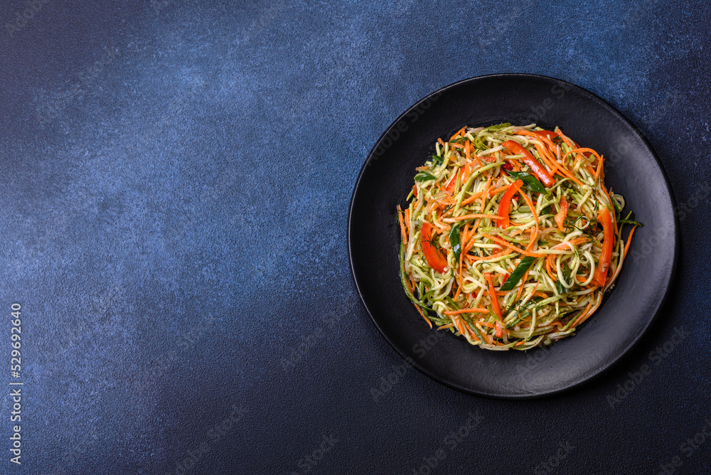 Fresh salad of sliced thin strips of carrot and zucchini on a concrete background Fresh salad of sliced thin strips of carrot and zucchini on a concrete background