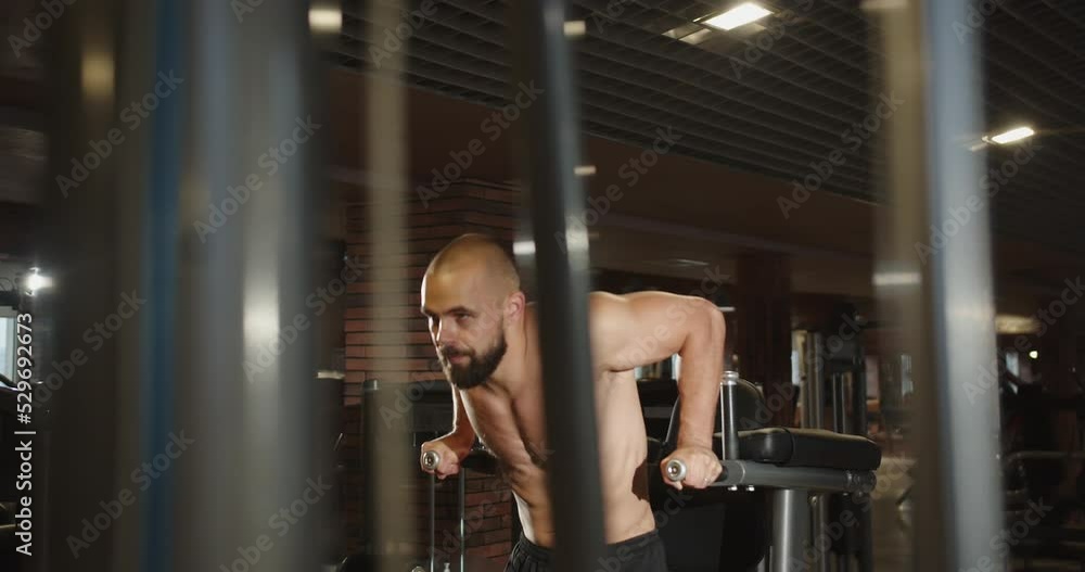 A professional athlete pulls up on the parallel bars in the gym A professional athlete pulls up on the parallel bars in the gym