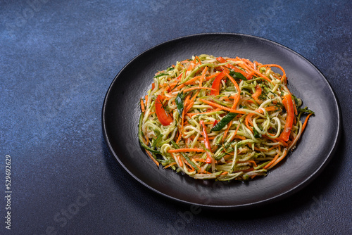 Fresh salad of sliced thin strips of carrot and zucchini on a concrete background