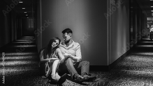 Couple in love sitting in floor of corridor of the hotelwalking along the corridor of the hotel