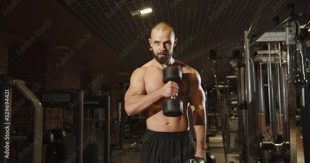 A man does sports in the gym holding dumbbells in his hands A man does sports in the gym holding dumbbells in his hands