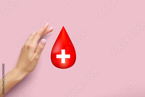 Female hand and drop of blood on pink background