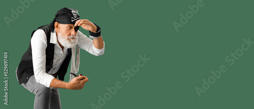 Mature pirate with smoking pipe on green background with space for text