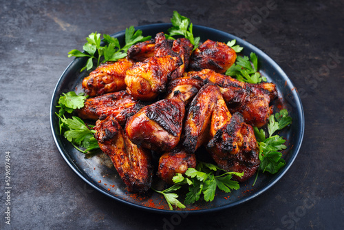 Traditional barbecue chicken wings and drumsticks with hot chili and coriander served as close-up on a rustic plate