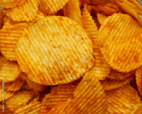 Top view of a lot of corrugated potato chips with peppers. Background image for snacks for beer.