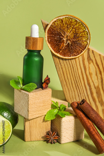 Composition with bottle of essential oil, spices and wooden decor on color background