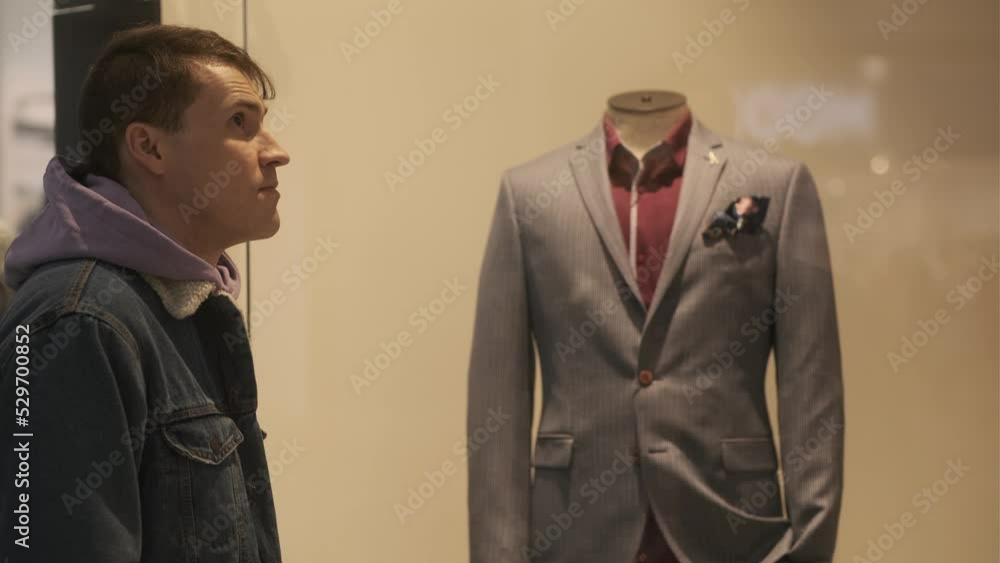 Portrait of young thoughtful man considering showcase in shopping center. Concept of shopping, dream, desire. Portrait of young thoughtful man considering showcase in shopping center. Concept of shopping, dream, desire.