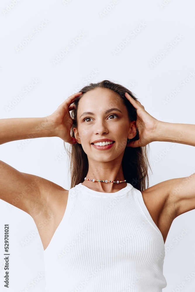 Portrait of a beautiful woman with tanned skin and a beautiful snow-white smile and brown natural long hair on her head posing against a white background touching her hair. Care of her long hair Portrait of a beautiful woman with tanned skin and a beautiful snow-white smile and brown natural long hair on her head posing against a white background touching her hair. Care of her long hair
