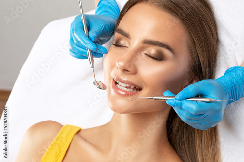 A dentist doctor treats caries on a tooth of a young beautiful woman in a dental clinic. Tooth filling.