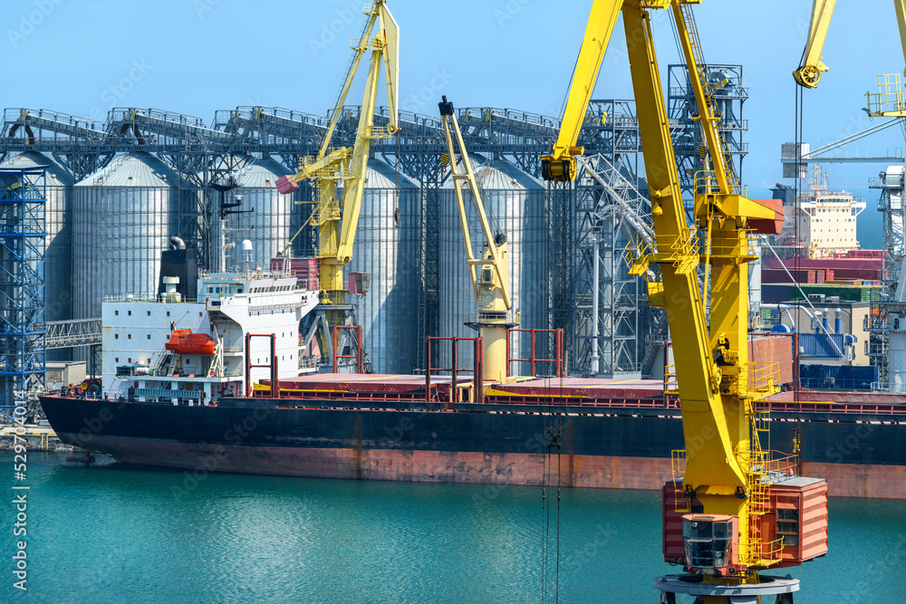 industrial seaport infrastructure, sea, cranes and dry cargo ship, grain silo, bulk carrier vessel and grain storage elevators, concept of sea cargo transportation industrial seaport infrastructure, sea, cranes and dry cargo ship, grain silo, bulk carrier vessel and grain storage elevators, concept of sea cargo transportation