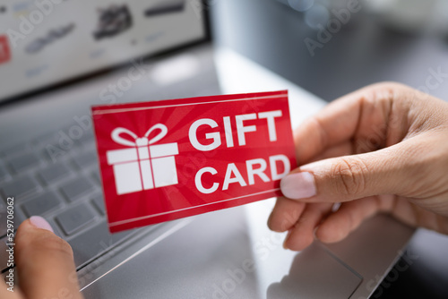 Woman Holding Red Gift Card While Typing photo