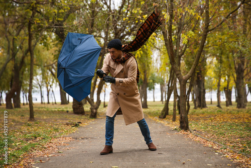 Konstfotografi Man with blue umbrella caught in gust of wind outdoors