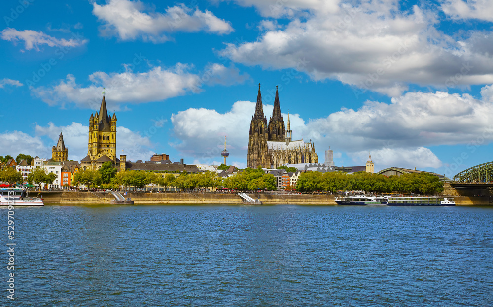 Cologne, Germany - July 9. 2022: Rhine riverside cityscape, St. Martin church and dom, blue summer sky