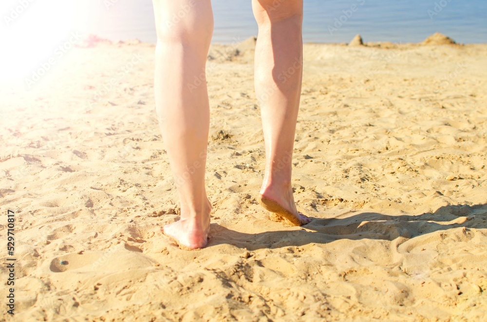 Summer concept: a beach with yellow sand and women's legs on a sunny summer day. Selective focus. Summer concept: a beach with yellow sand and women's legs on a sunny summer day. Selective focus.