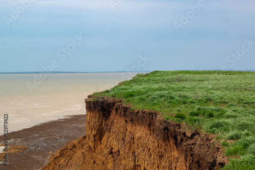 Clay rocks with blue sky and water. Coastal break near the lake. photo