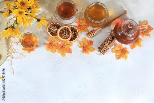 Autumn banner with hot tea in a glass cup  honey and spices on the background of seasonal flowers and leaves  space for text  cozy warm autumn concept  hygge style  selective focus  top view